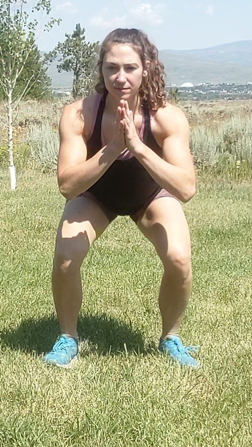 A squat with hips just above 90 the knees, taken from the person facing the camera directly. The knees are aligned directly in line above the feet.