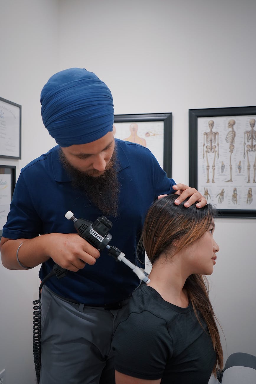 Chiropractor treating woman's neck with a machine that is claimed to put a joint back into place. It makes me cringe when I hear this, because this is not accurate and not what causes relief. 