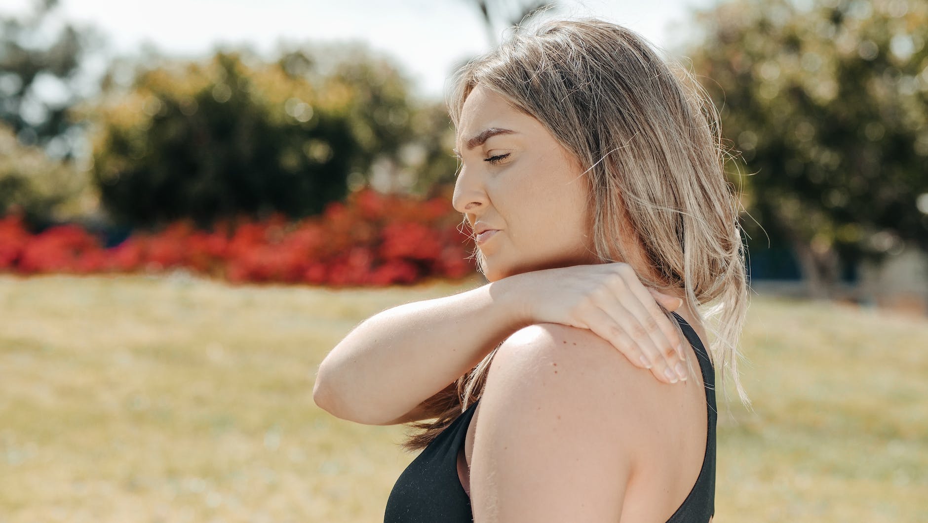 a woman in black tank top touching her shoulder